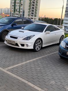 several cars parked in a parking lot next to tall buildings