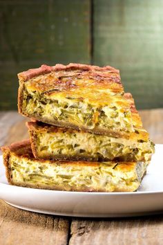 three pieces of quiche stacked on top of each other in a white plate with wood background