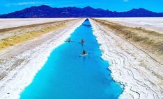 a body of water with mountains in the background and snow on the ground around it