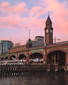 an old building with a clock tower next to the water and buildings in the background