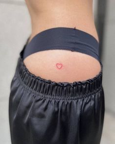 a woman's stomach with a small heart tattoo on her lower back, and the bottom half of her pants