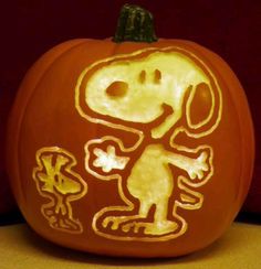 a pumpkin with a drawing of a dog on it's face and the word snoop written in white