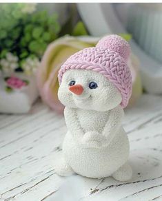 a small white snowman with a pink hat on