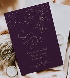 an elegant save the date card on top of some wedding rings and envelopes with gold confetti