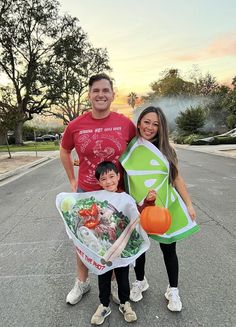 a man and two women standing next to each other in the street holding kites