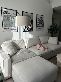 a living room with white furniture and pictures on the wall