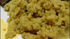 closeup of mashed potatoes on a white plate with mustard sauce in the background