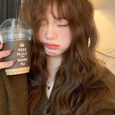 a woman with long hair holding a cup of coffee