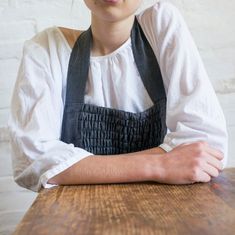 a woman sitting at a wooden table with her arms crossed and looking to the side