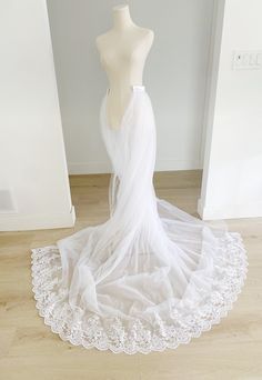 a white wedding dress on a mannequin in front of a wall and floor