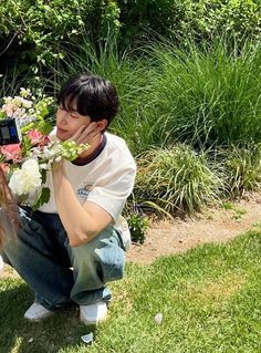 a man kneeling down with flowers in his hand and a cell phone to his ear