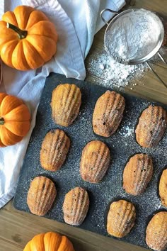 several muffins on a baking tray with pumpkins and flour in the background