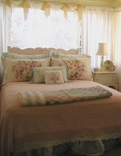 a bed sitting in a bedroom next to a window with curtains on the windowsill