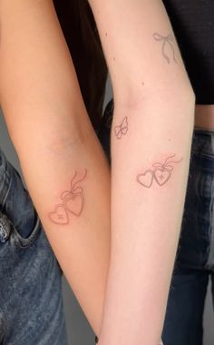 two girls with matching tattoos on their arms