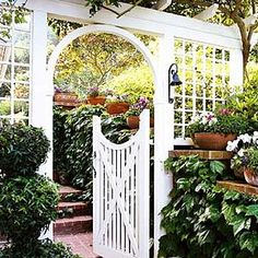 a white arbor with potted plants on it