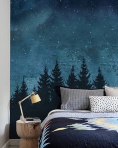 a bed room with a neatly made bed and a night sky mural