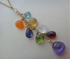 A cascade of rainbow colors dangle from a gold filled chain. Faceted multicolor gemstone briolettes are carefully wrapped with gold filled wire and are suspended from the gold filled chain dangle. A faceted moonstone rondelle begins the dangle and also secures the dangle to the gold filled chain. A gold filled clasp and closed jump ring are secured to the chain with faceted moonstone rondelles.  * The faceted gemstones are apatite, carnelian, citrine, iolite, moonstone, peridot, garnet, and amethyst briolettes. * The dangle is 2 & 3/16" long. *  From end to end, not including the dangle, the necklace is just shy of  17 inches.    * All gold is 14kt.                                             * PLEASE NOTE: PHOTOS ARE DELIBERATELY TAKEN UP CLOSE TO SHOW DETAIL, SO JEWELRY LOOKS LARGER THAN Multicolor Wire Wrapped Dangle Necklaces, Jewelry Looks, Rainbow Gemstones, Rainbow Necklace, Necklace Gemstone, Gold Chain Necklace, Faceted Gemstones, Gold Filled Chain, Necklace Handmade