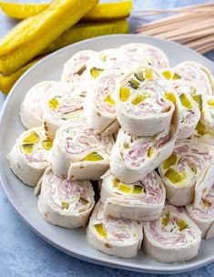 a white plate topped with rolls and pickles next to two yellow squashsticks