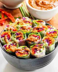 a plate full of vegetable spring rolls with dipping sauce in the bowl next to it