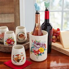 four wine glasses sitting on top of a wooden table next to bottles of wine and cheese