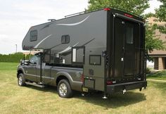 a truck with a camper attached to it's bed parked in the grass