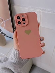 a person holding up a pink phone case with a heart on it