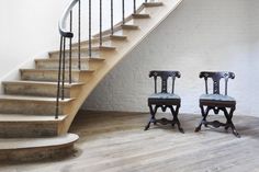 two chairs sitting in front of a stair case next to a set of wooden steps