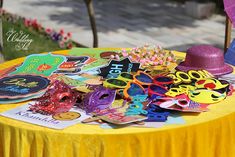 a yellow table topped with lots of party decorations and masks on it's side