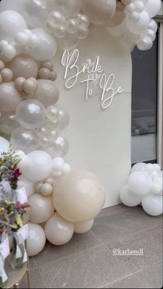 the entrance to a bridal to be event with white balloons and flowers in vases