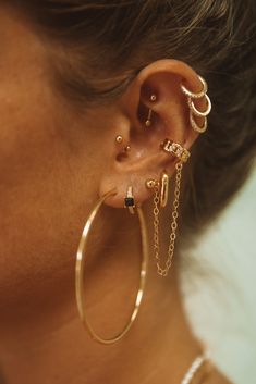 a close up of a person wearing gold ear rings and chain around their ears,