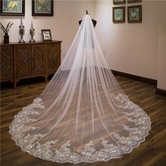 a wedding veil hanging from the ceiling in a room with pictures on the wall and wooden flooring