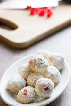 a white plate filled with powdered donuts on top of a wooden cutting board