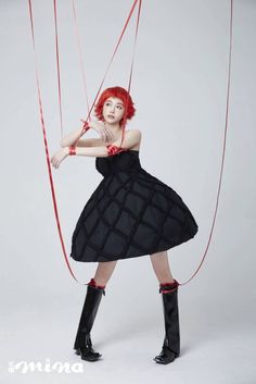 a woman with red hair and black dress holding two strings