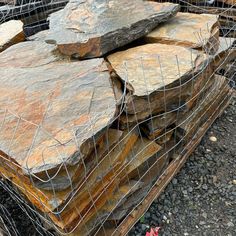 several large rocks stacked on top of each other in a wire cage with red flowers