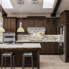 a large kitchen with wooden cabinets and marble counter tops, along with two bar stools