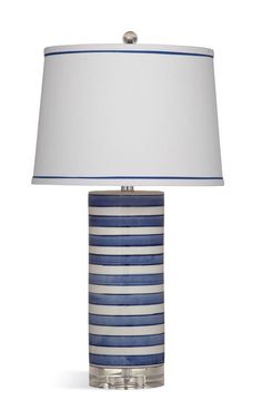 a blue and white striped lamp with a white shade on the top, sitting against a white background