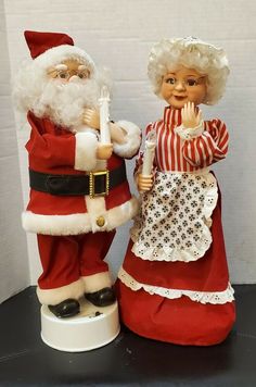 two santa claus figurines standing next to each other