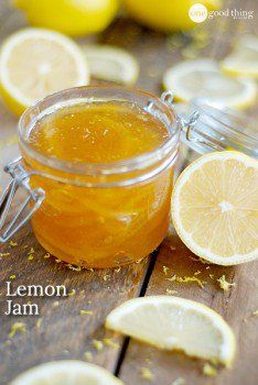 a glass jar filled with lemon jam sitting on top of a wooden table next to sliced lemons