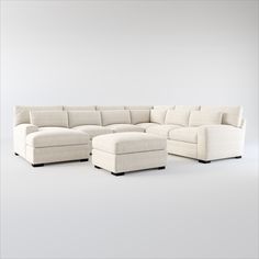 a white sectional couch with ottoman and footstool