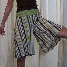 a woman standing in front of a white curtain with her legs crossed and one hand on her head