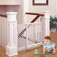 a baby crawling on the floor in front of a banister and toy car set