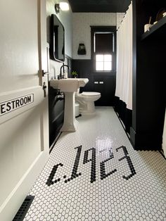 a bathroom with black and white tile flooring and walls, along with a toilet and sink