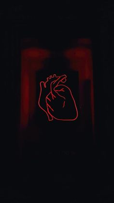 a red neon sign in the dark with a heart on it's back side