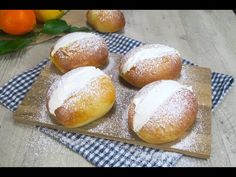 four powdered donuts on a wooden board with blue and white checkered napkin