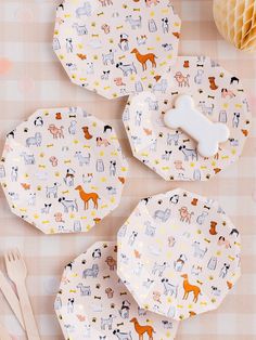 three paper plates with dogs and cats on them next to utensils, honey combs and honeycombs