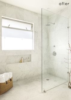 a bathroom with a glass shower door and white marble walls