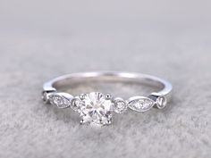 a white gold engagement ring with an oval cut diamond surrounded by three small round diamonds