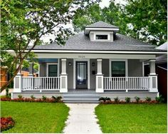 a gray house with white trim and porches