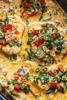 a pan filled with chicken and spinach covered in cheese, sauce and seasoning