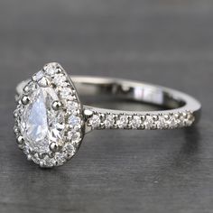 an engagement ring with a pear shaped diamond surrounded by small round diamonds on the band